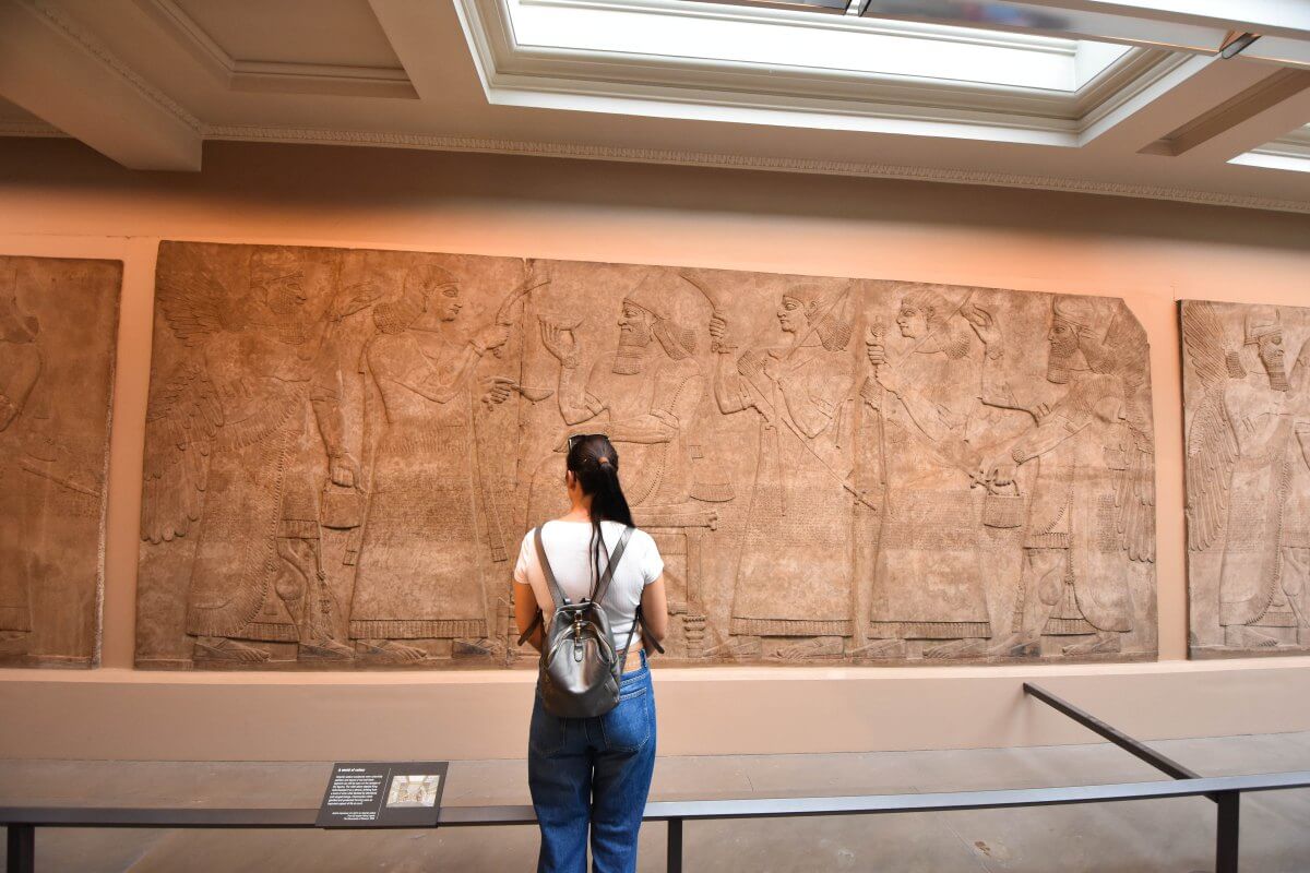 Martina standing before Assyrian stone relief, Nimrud